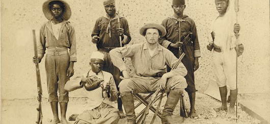 Th. Bumiller (m.) in kolonialer Pose mit ungenannten Teilnehmern in Deutsch-Ostafrika, zw. 1889 u. 1893.